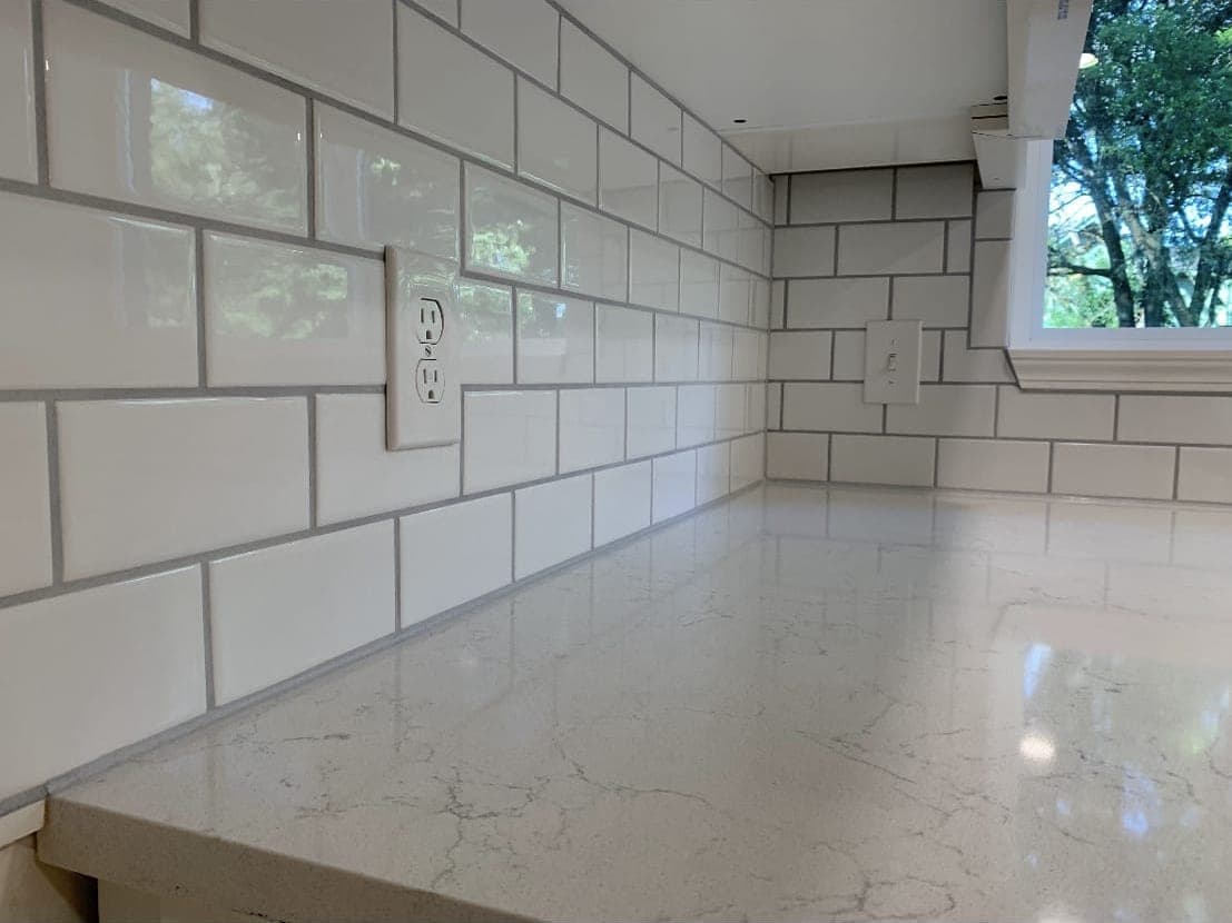 White subway tile splashback meeting a marble counter and window sill