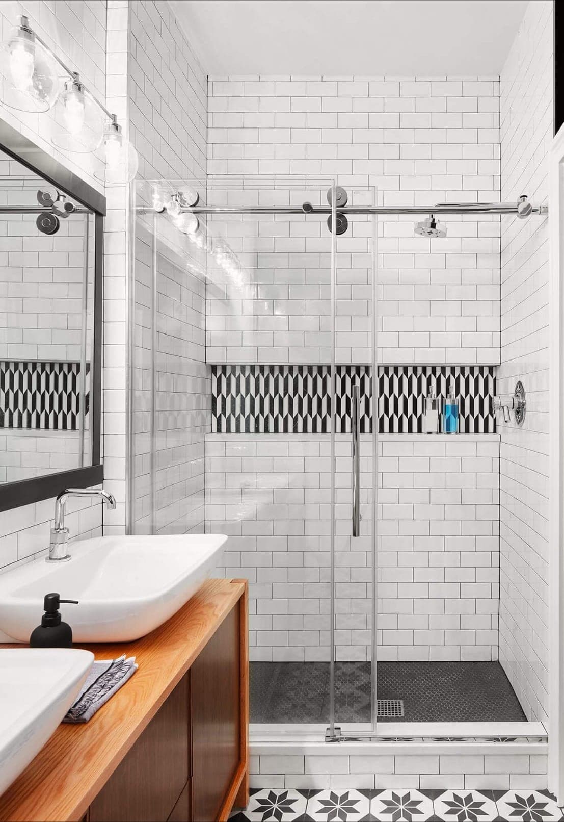 Walk-in glass shower in white subway tile with a patterned accent band