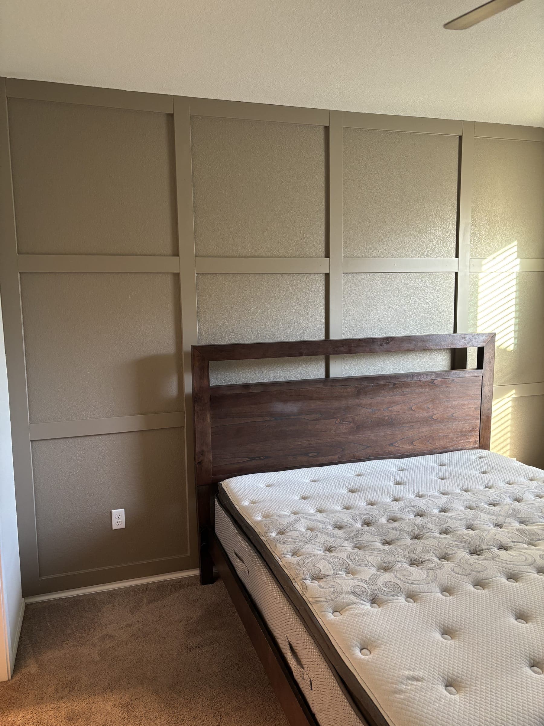 The finished panelled wall behind a walnut bed frame
