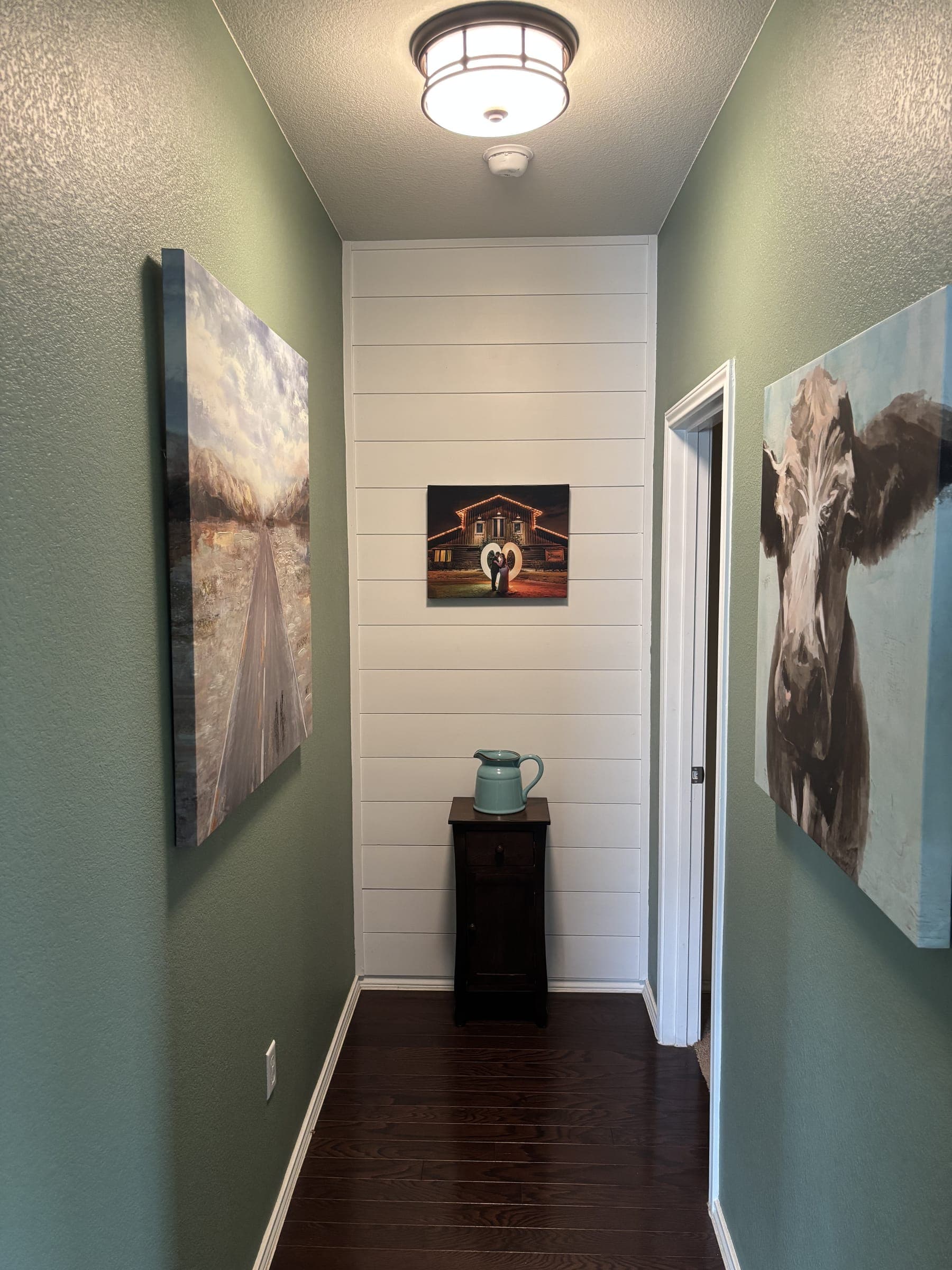 The same hallway with a shiplap accent wall and hung artwork