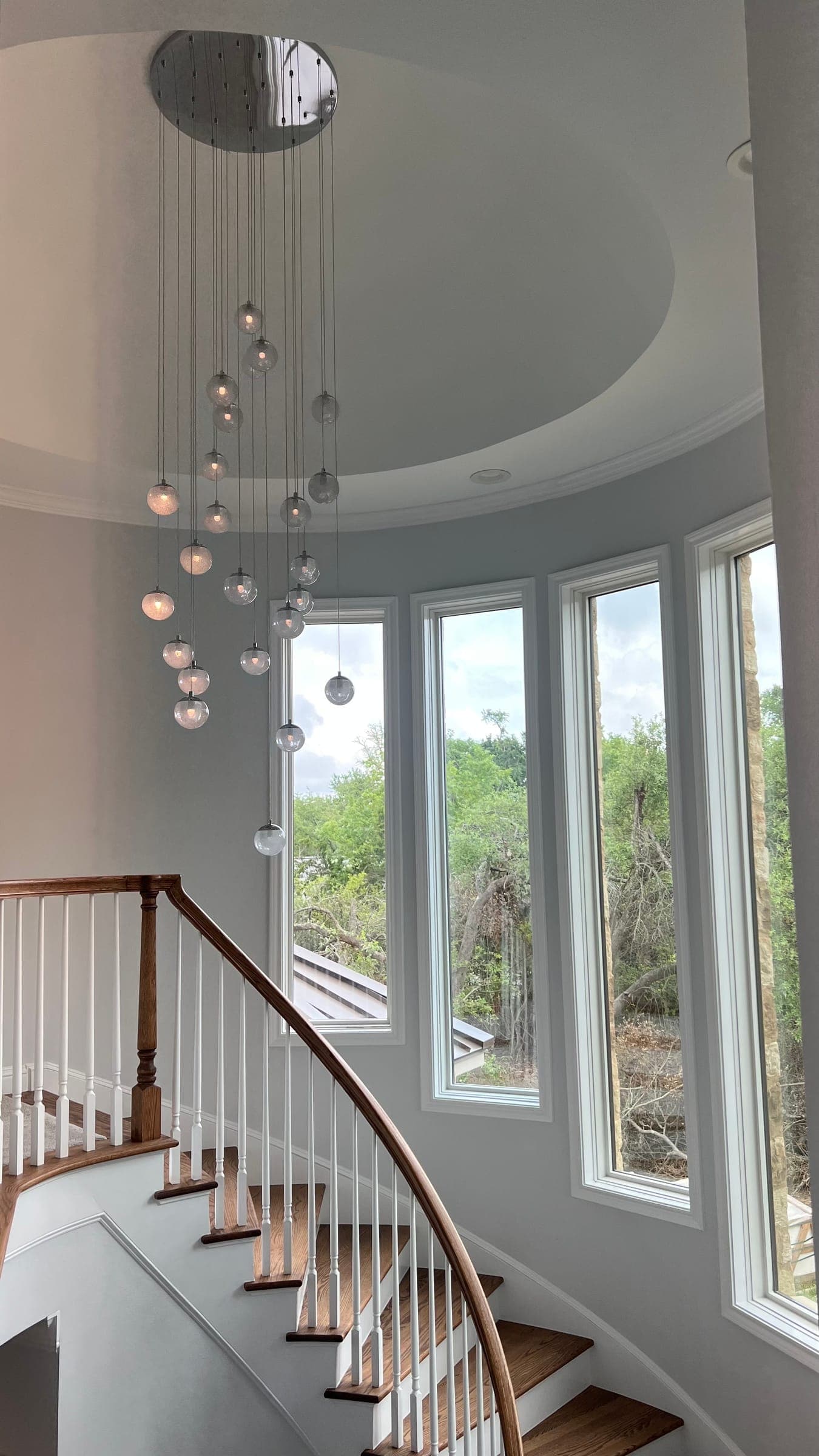Glass globe pendants hung against tall windows in a curved stairwell