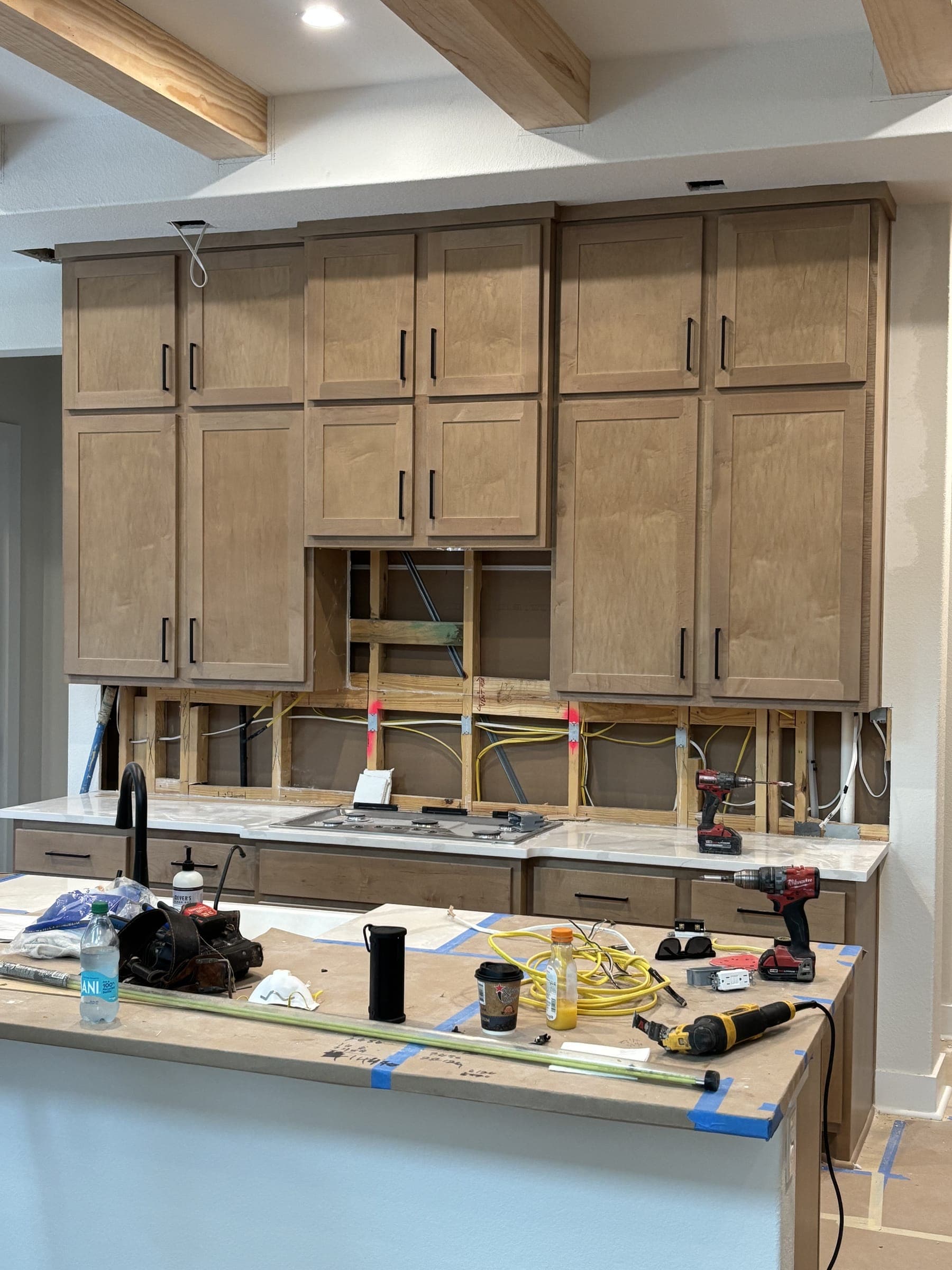 Kitchen stripped back mid-build, cabinet boxes open and tools on the counter