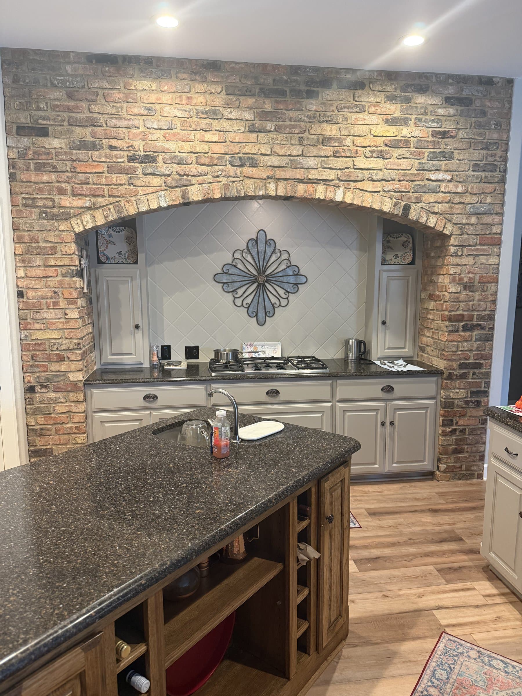 Kitchen range nook framed by a reclaimed brick archway with a tiled medallion backsplash