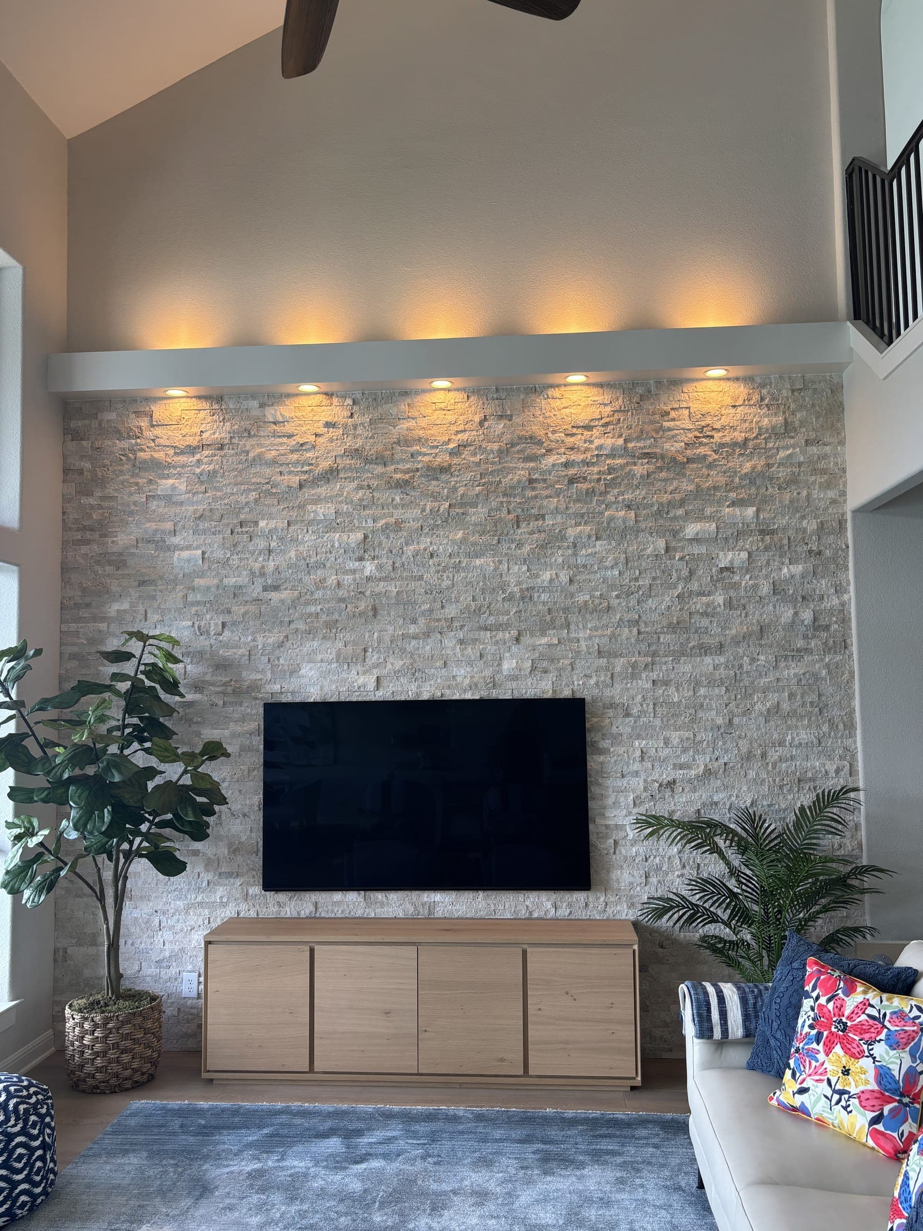 Stacked stone fireplace wall with recessed uplighting and a mounted television
